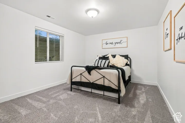 White walls with gray carpet, a single window, and a ceiling-mounted light fixture