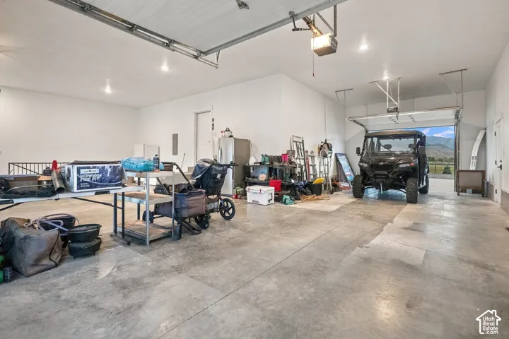Spacious garage with concrete flooring, multiple overhead garage doors, and overhead lighting fixtures