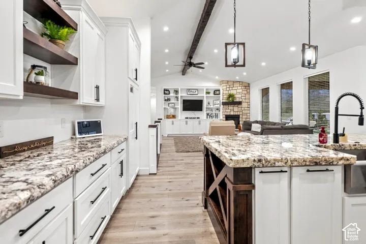 Kitchen featuring white cabinetry, stone countertops, wood-finish flooring, and built-in shelving