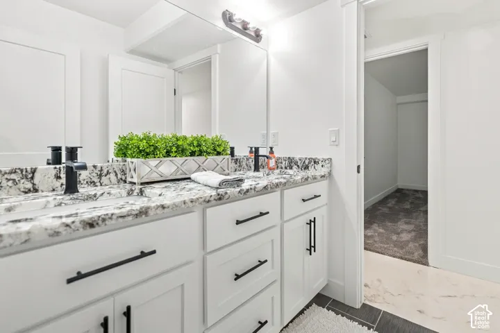 Dual vanity with white cabinetry, black hardware, and speckled countertops
