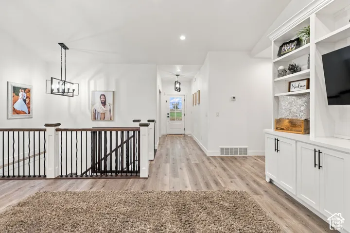 White walls, recessed lighting, wood-finish flooring, white built-in cabinetry, and a black metal and wood railing
