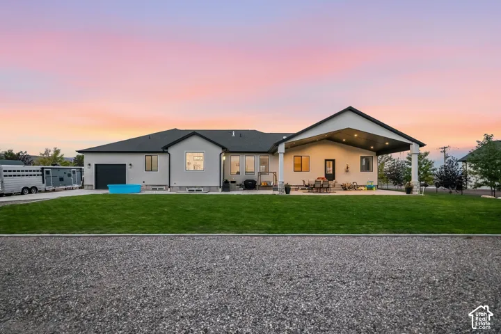 Single-story residence featuring a covered patio, expansive lawn, and a two-car garage