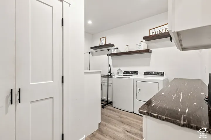 White shaker cabinetry with modern black pulls, wood-finish flooring, dark stone-finish countertop, white walls, and recessed lighting