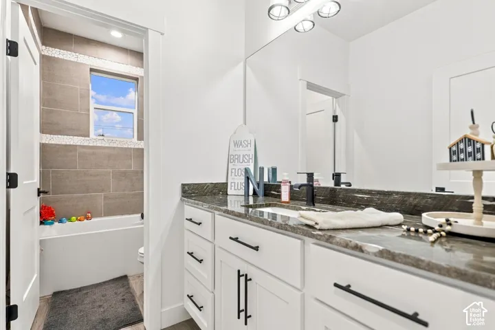 Bathroom vanity featuring a dark stone countertop, undermount sink, and black wall-mounted faucet
