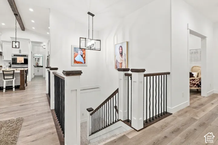 Open-concept living space with wood-finish flooring, white cabinetry, and a kitchen island with seating