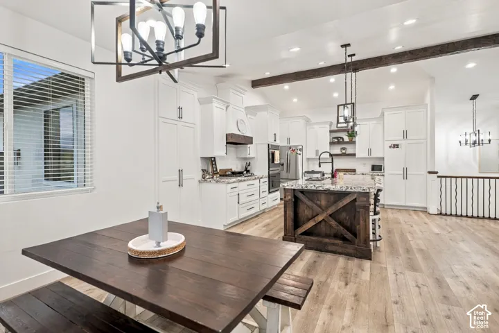 Open-concept kitchen with white cabinetry, granite countertops, wood-finish flooring, and a dark wood island
