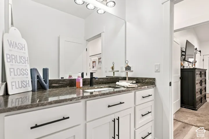 Vanity with a dark patterned countertop, integrated sink, and matte black faucet