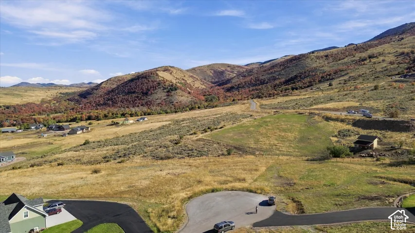Expansive mountainous terrain with varied vegetation, including areas of green grass and autumn-colored trees