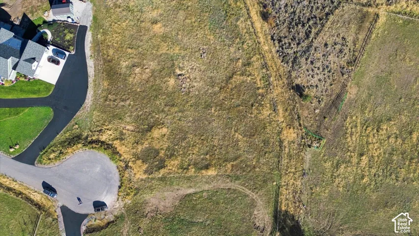 Expansive undeveloped land with varied terrain, bordered by a paved road and cul-de-sac