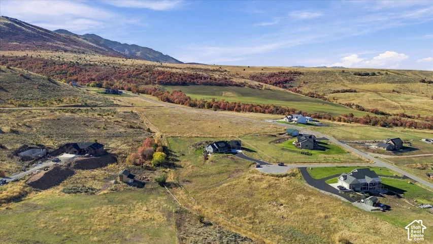 Expansive property featuring undeveloped land, established homes, paved roads, and distant mountains