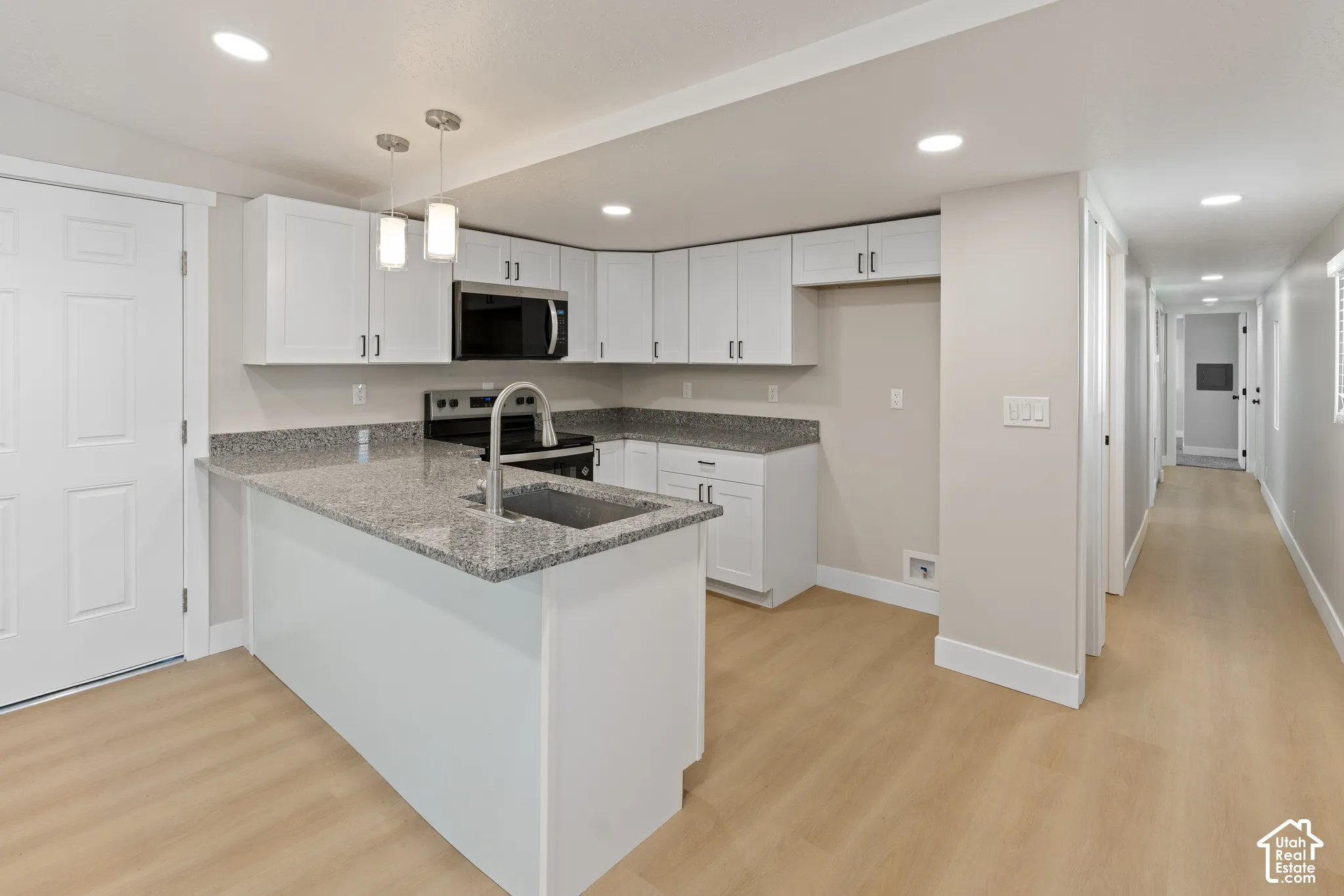Kitchen featuring white cabinetry, stainless steel appliances, granite countertops, and wood-finish flooring