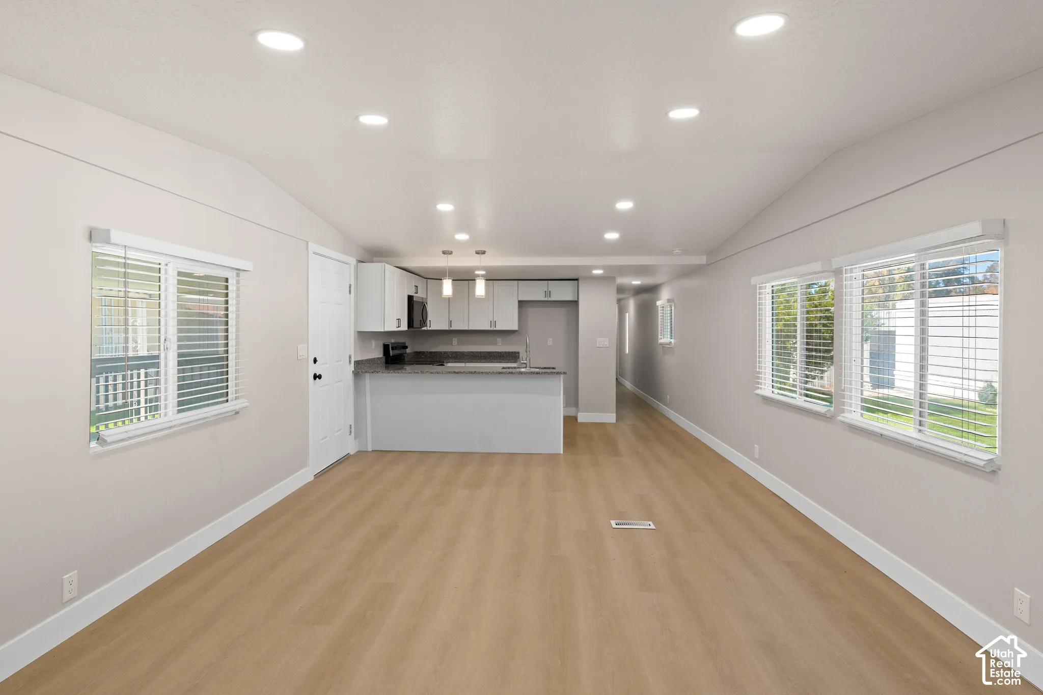Open-concept living space featuring wood-finish flooring, recessed lighting, and a vaulted ceiling