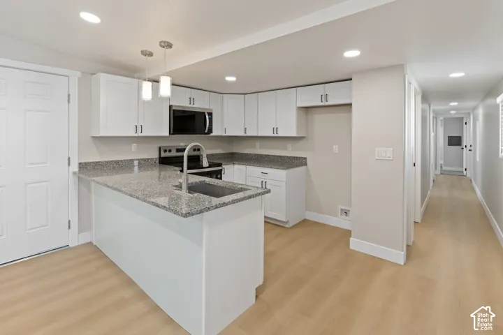 Kitchen featuring white cabinetry, stainless steel appliances, granite countertops, and wood-finish flooring