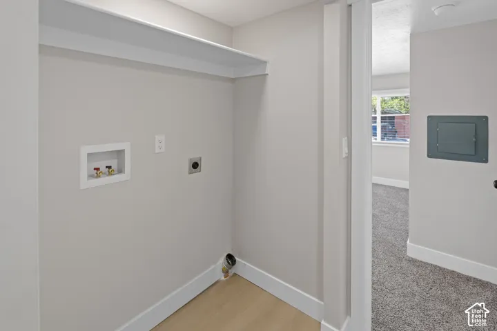 Dedicated laundry area with hookups, overhead shelving, and wood-finish flooring