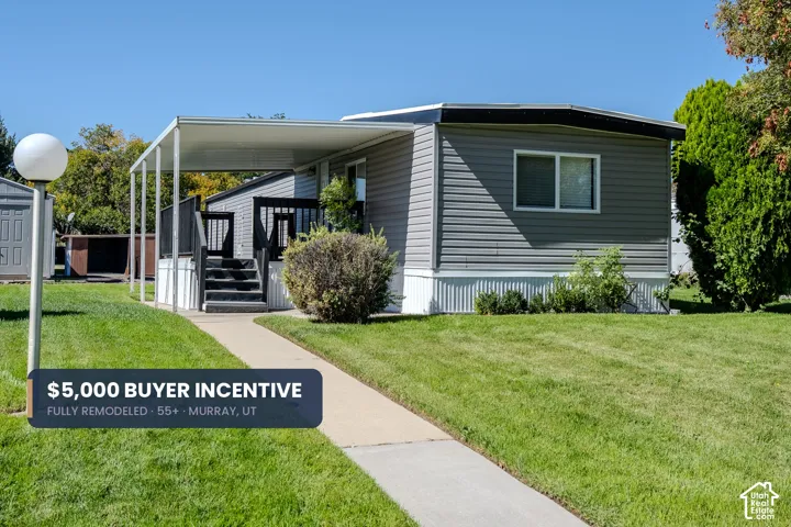 Light gray siding exterior with white trim, covered porch with dark wood railing, concrete walkway, and a landscaped lawn