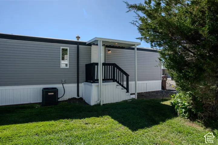 Exterior featuring gray horizontal siding, white vertical skirting, a covered porch with dark railings, and an exterior HVAC unit