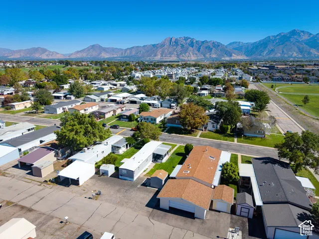 Expansive neighborhood with diverse residential structures and mature trees, featuring a distant mountain range