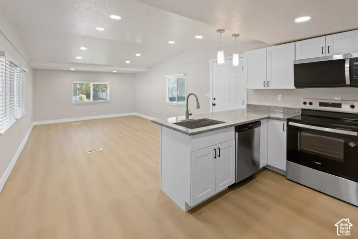Open-concept living area featuring wood-finish flooring, recessed lighting, and multiple windows