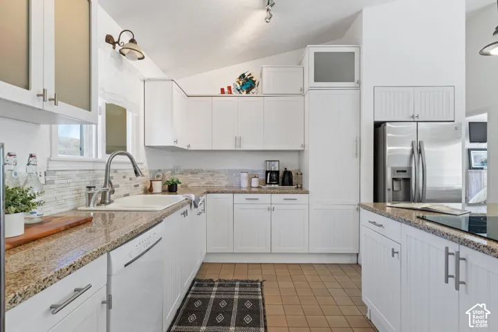 Kitchen featuring white cabinetry, stone-finish countertops, stainless steel appliances, and a tiled backsplash