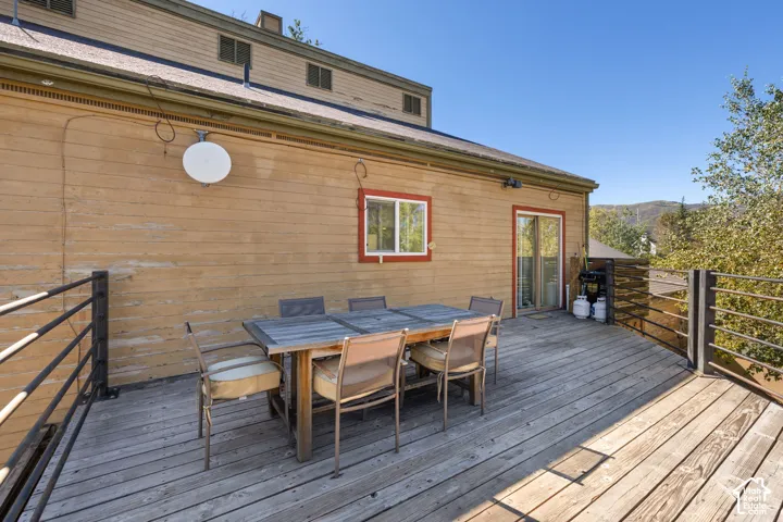 Expansive wood deck with metal railing, adjacent to a sliding glass door and an additional window