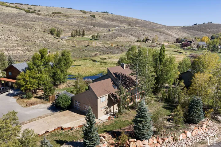 Sloped roofline residence featuring an attached two-car garage, concrete driveway, and natural rock retaining walls