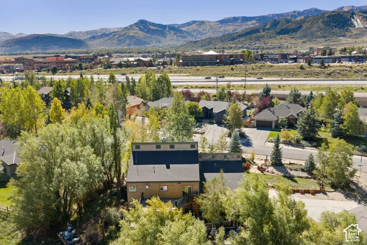 Mountain range backdrop, mature trees, residential neighborhood setting, visible roadway infrastructure, and varied architectural styles