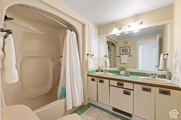 Dual vanity with oval sinks, green tiled countertop, and integrated storage cabinetry