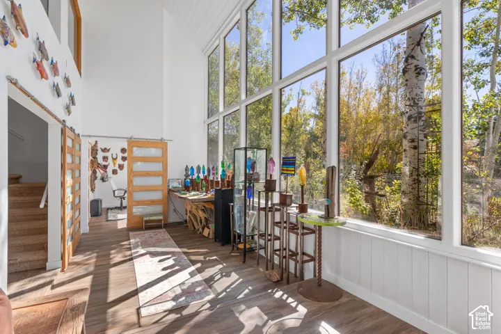 Two-story great room with vaulted ceiling, wood-finish flooring, and expansive floor-to-ceiling windows