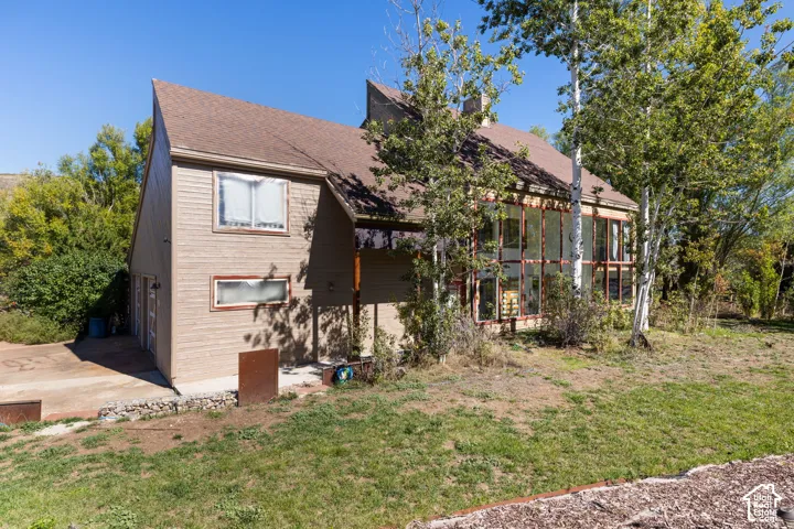 Pitched roofline, multi-pane windows, wood-sided exterior, attached garage, mature trees