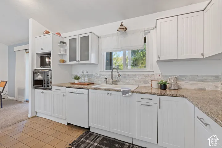 White cabinetry, granite-finish countertops, subway tile backsplash, stainless-steel sink, and tile flooring