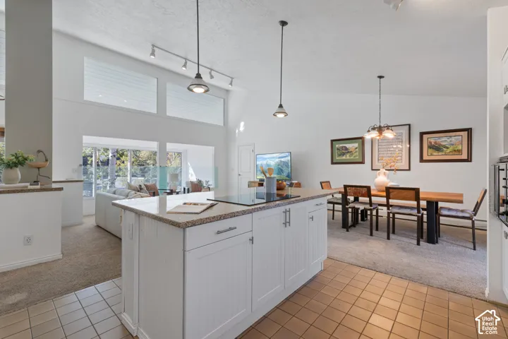 Kitchen island with an integrated cooktop, white paneled cabinetry, and a light-toned countertop
