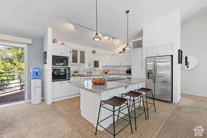 Kitchen featuring white cabinetry, stainless steel appliances, a center island with a light-colored countertop, and recessed lighting