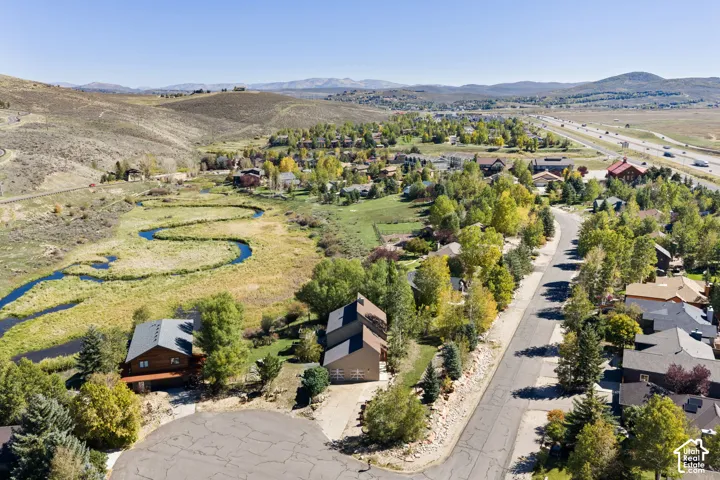 Aerial overview showcasing a winding river, distant mountains, a residential area with mature trees, and a road network