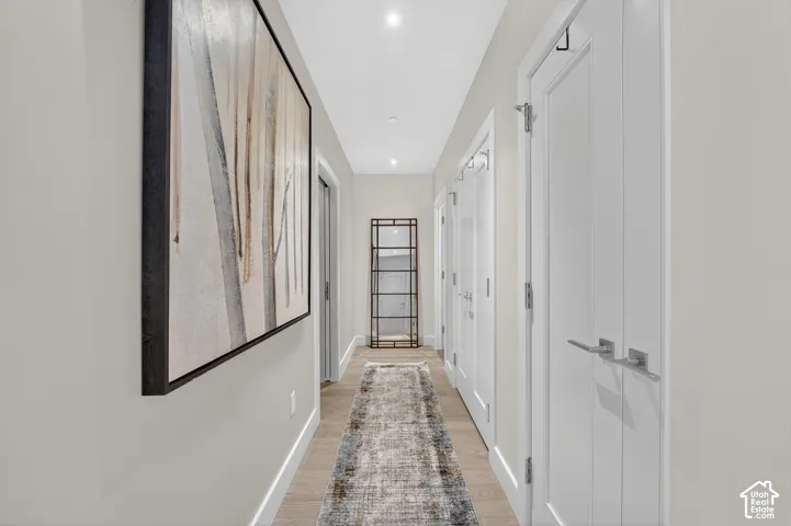 Recessed lighting, light-toned walls, wood-finish flooring, and white panel doors with contemporary hardware