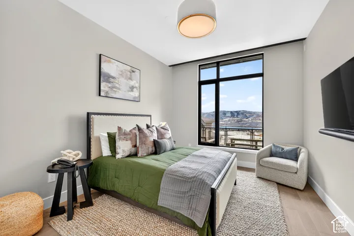 Expansive window with mountain and distant property views, light wood-finish flooring, recessed ceiling lighting, and a neutral wall palette