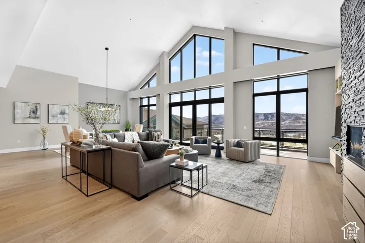 Vaulted ceiling, expansive windows, light wood-finish flooring, built-in fireplace, and stone-finish accent wall