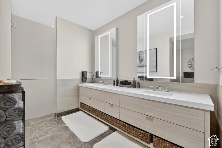 Dual illuminated mirrors over a light wood-finish vanity with ample storage