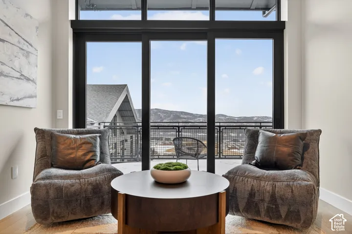 Full-height sliding glass doors with dark frames, wood-finish flooring, and a balcony with metal railings