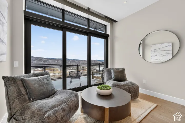 Full-height sliding glass doors with transom windows, engineered wood flooring, recessed ceiling lighting, and a mounted wall mirror