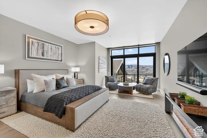 Expansive window wall with mountain scenery, recessed ceiling lighting, light wood-finish flooring, a contemporary ceiling fixture, and a built-in media console