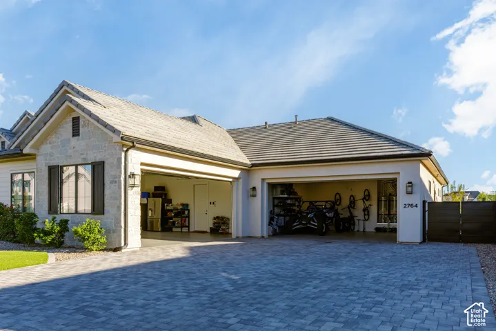 Stone facade accentuating the front elevation, two-car garage, paver driveway, and a tiled roof