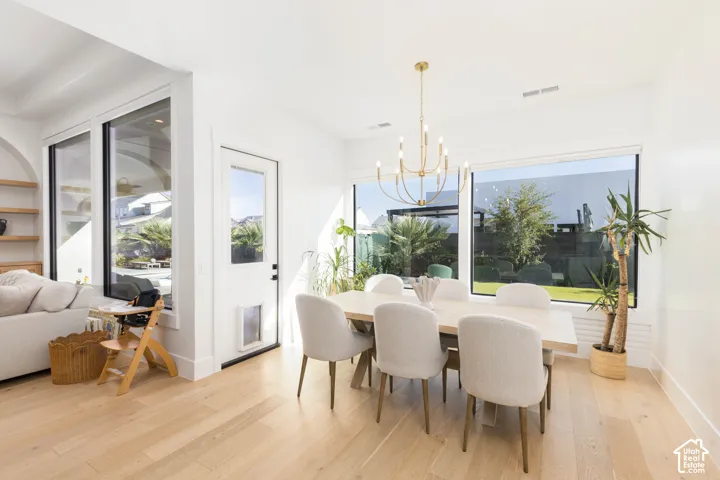 Dining area with a gold chandelier, wood-finish flooring, and large windows providing abundant natural light