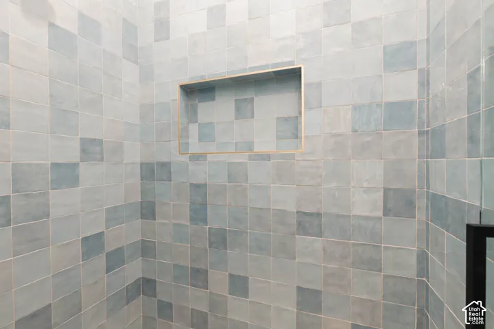 Tiled shower enclosure featuring varied blue and gray square tiles