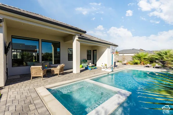 Outdoor pool with an integrated spa, expansive paver patio, and mature palm landscaping