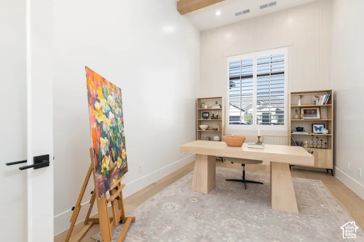 Vaulted ceilings with exposed wood beams, wood-finish flooring, and shiplap accent wall