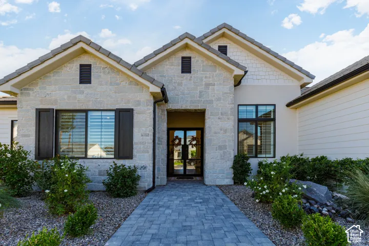 Stone and siding exterior with dark-framed windows, a paver walkway, and structured landscaping