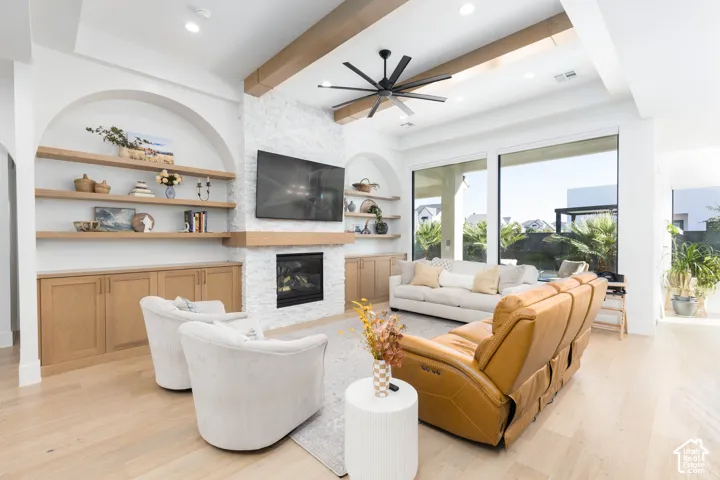 Living area featuring a gas fireplace with a stacked stone surround, built-in shelving with wood cabinetry, and wood-finish flooring