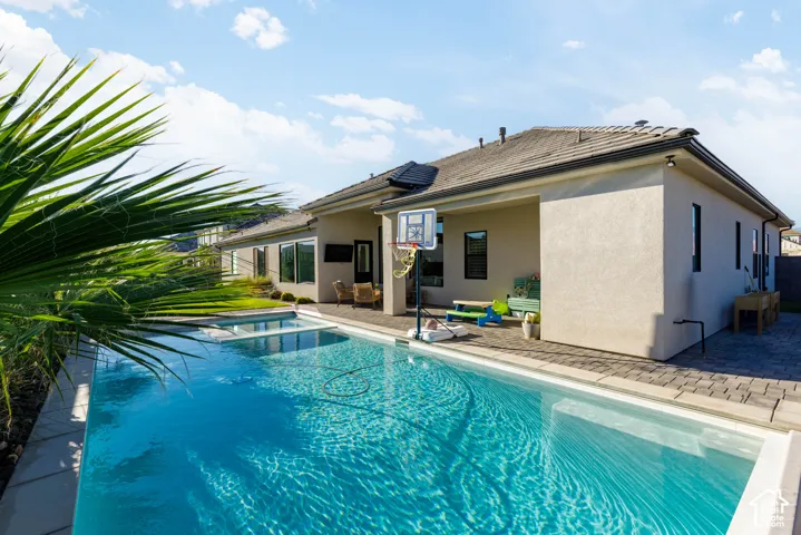 Large swimming pool with integrated spa, paver patio, stucco exterior, and tiled roof