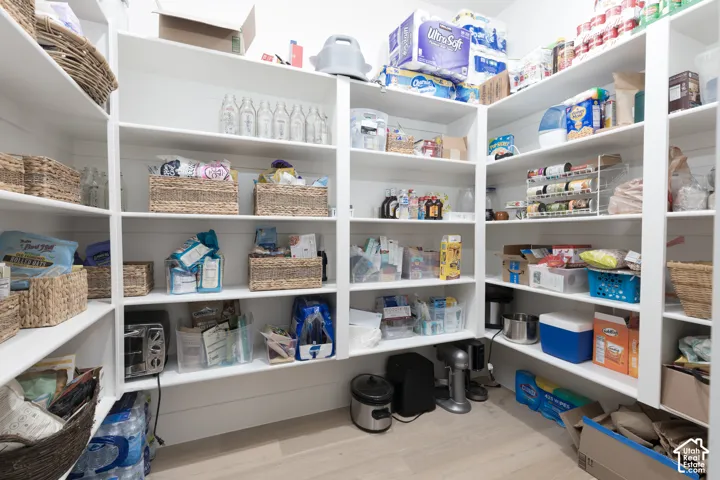 Expansive pantry featuring ample built-in shelving, durable wood-finish flooring, and bright white finishes