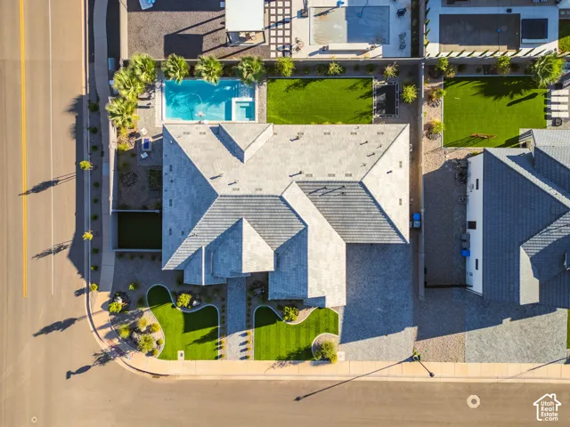 Gabled roofline, stone paver driveway, manicured front lawn, private swimming pool, and artificial turf landscaping